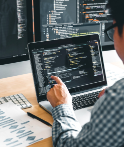 Modern office setup with developers working collaboratively on app projects, featuring screens displaying app designs, coding, and testing, representing a top app development company in Noida.