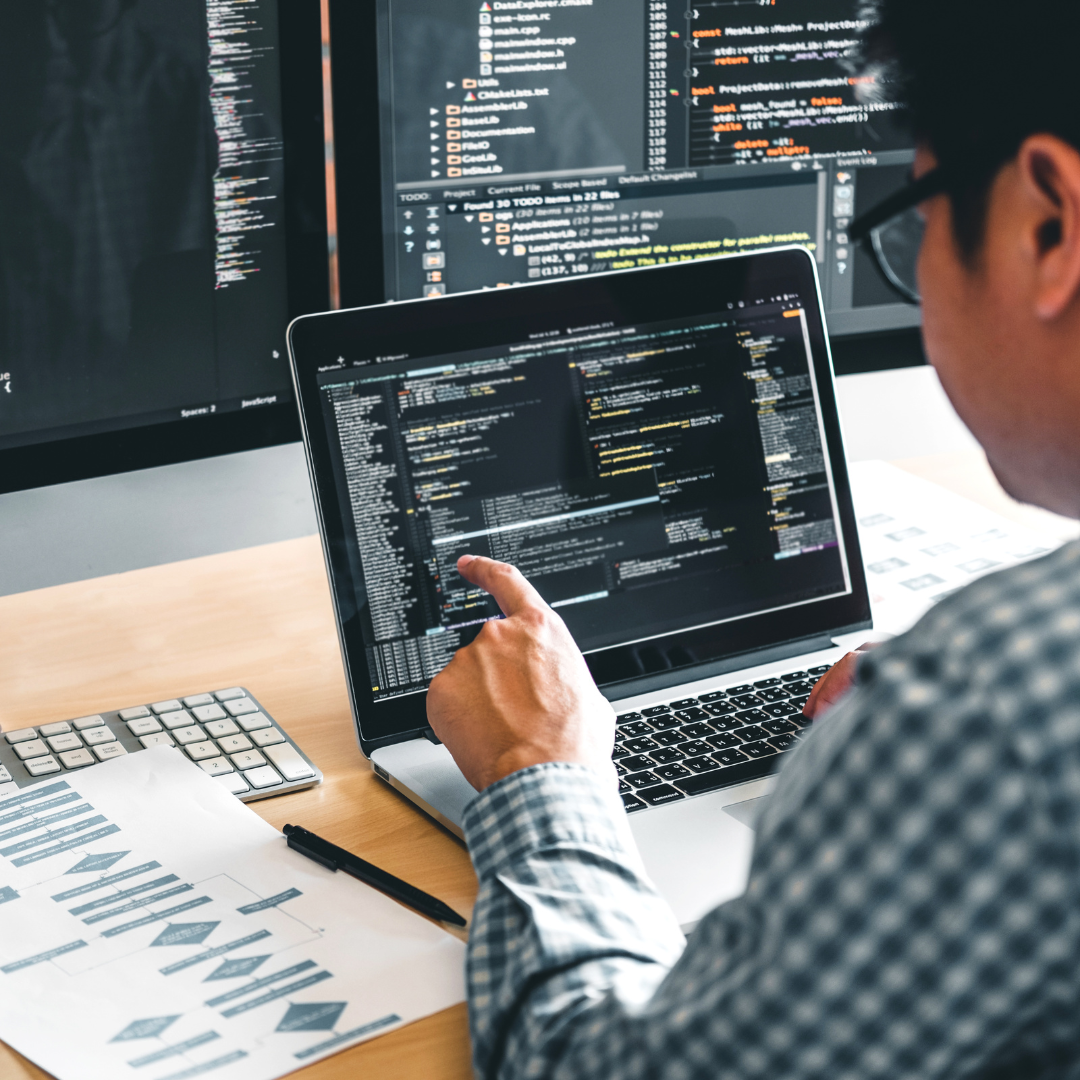 Modern office setup with developers working collaboratively on app projects, featuring screens displaying app designs, coding, and testing, representing a top app development company in Noida.